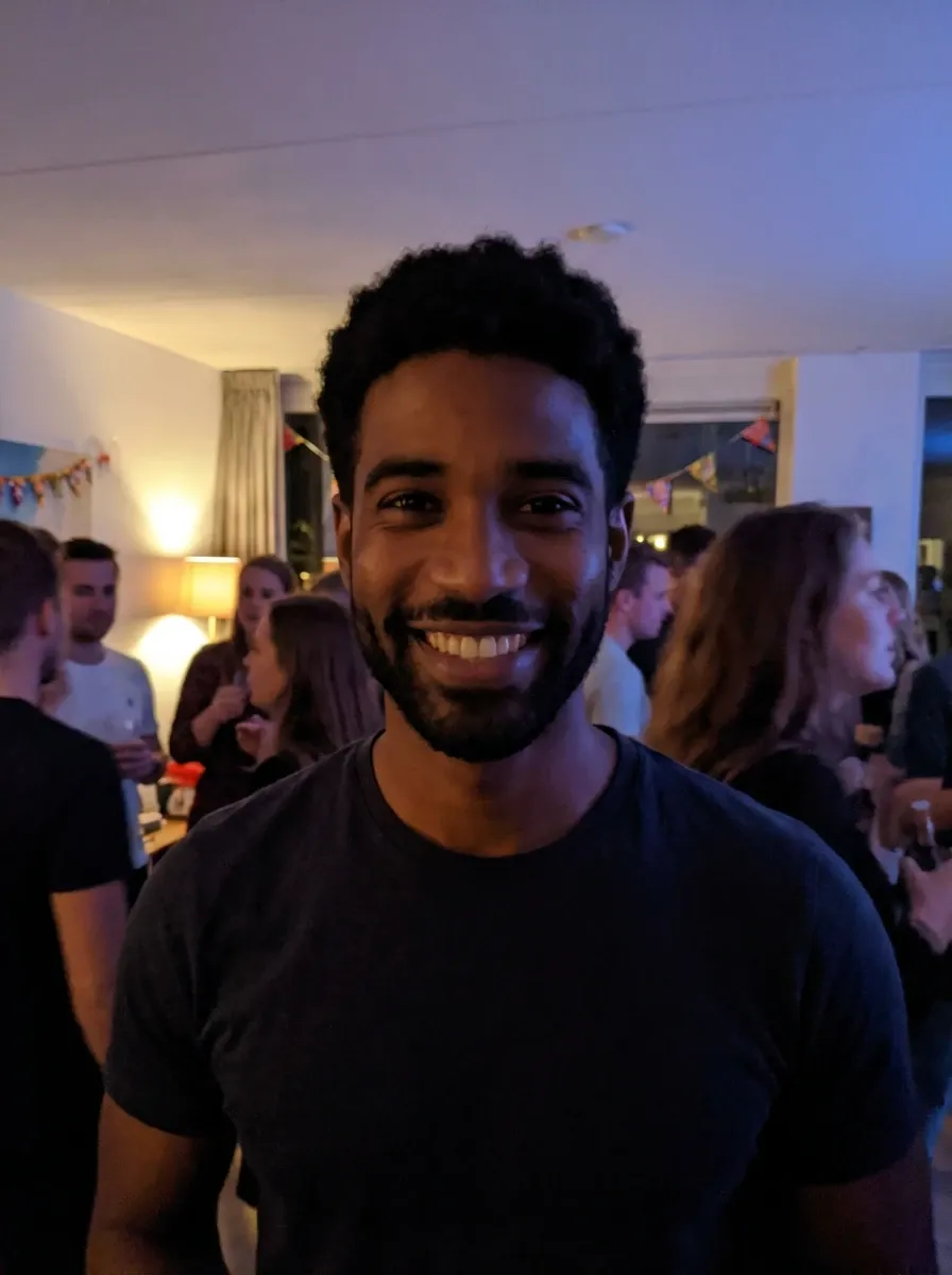Original selfie input — smiling man in a dark T-shirt at a social event